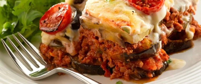 Tradional lamb Moussaka on a plate with a fork is part of my food lovers guide to this dreamy Iconic Greek food