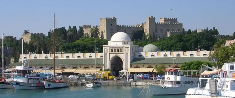 Mandraki Marina and Port building entrance with the Palace of Grand Master Rhodes in the background