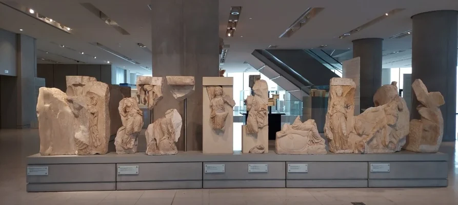 Walking Nike, two Nike adorning a trophy with weaponry, calm Nike, Nike holding a shield, Godess Athena seated on a rock, at the Acropolis Museum in Athens