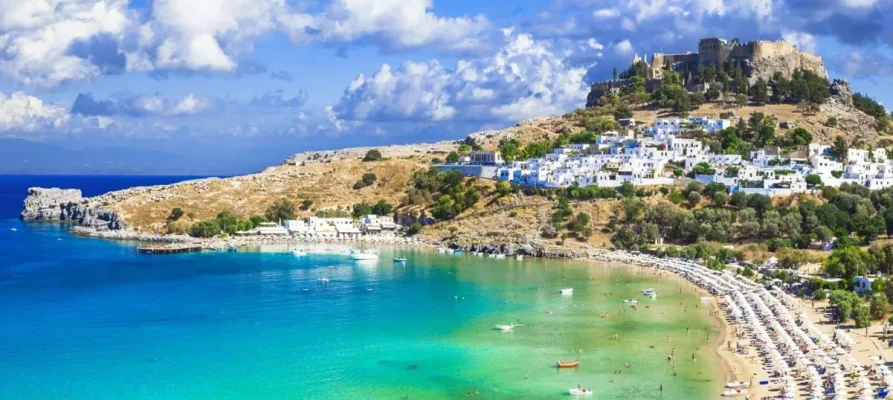 Lindos Bay, the Lindos Acropolis, and the whitewahsed houses of Lindos Village on Rhodes, Dodecanese