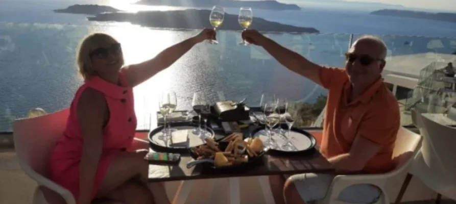 Two wine glasses clinking during sunset over the caldera on Santorini as part of the Santorini: Guided Wineries Private Tour with Wine Tastings