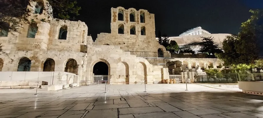 Night-time at the the front of the Odeon of Herodes Atticus on the Acropolis of Athens. The Parthenon is just visible towards the top -right