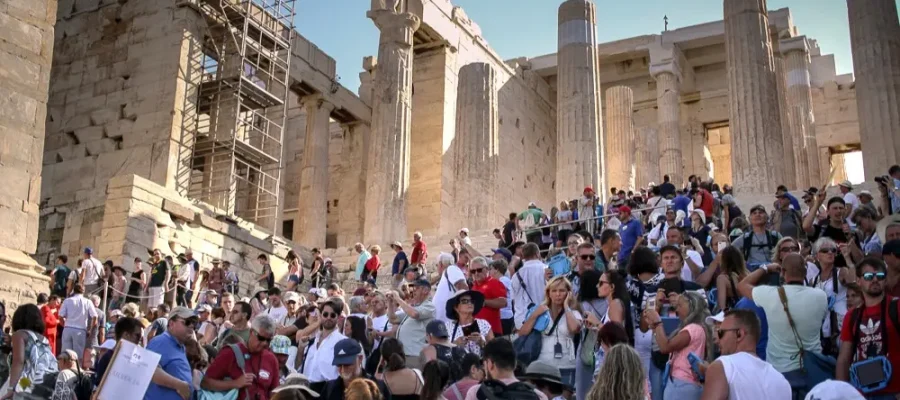 busy scene of tourists visiting the Acropolis at the Acropolis entrance in Athens, with a diverse group of individuals and families preparing to visit the historic site on a sunny day.