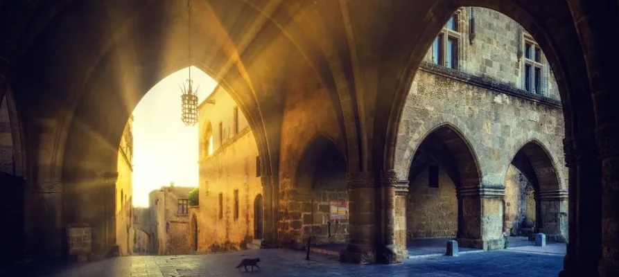 Two very large medieval archways, with one lit by the golden rays of the sun. This is the Street of the Knights of Rhodes, Greece