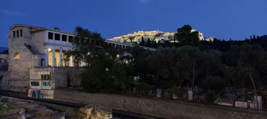 Night-time photo of the Acropolis of Athens as viewed from just outside the entrance to the Ancient Agora of Athens. The Stoa of Attalos is on the left.