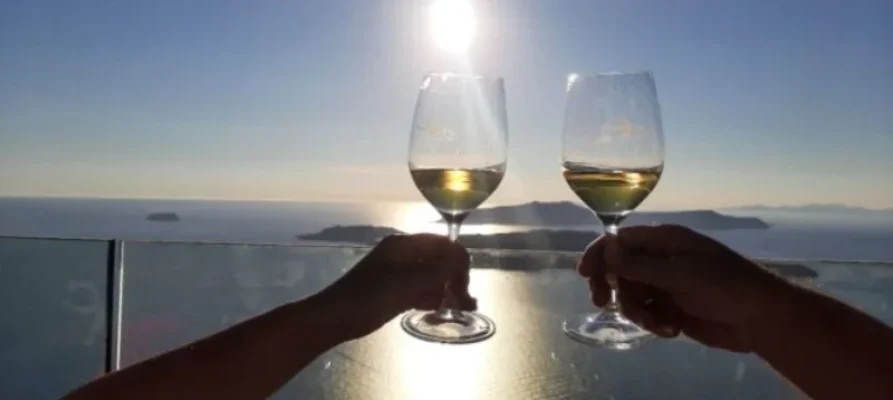 Two wine glasses being held during sunset over the caldera on Santorini as part of the Santorini: Guided Wineries Private Tour with Wine Tastings