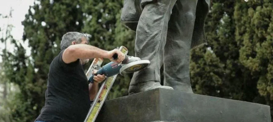 A determined member of the leftist group PAME uses a metal grinder on the Truman statue during a protest in April 2018