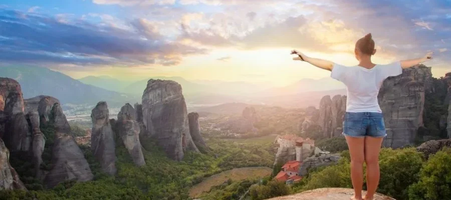 Woman stood on rock viewing the incredible rock formations and monasteries at Meteora, Greece