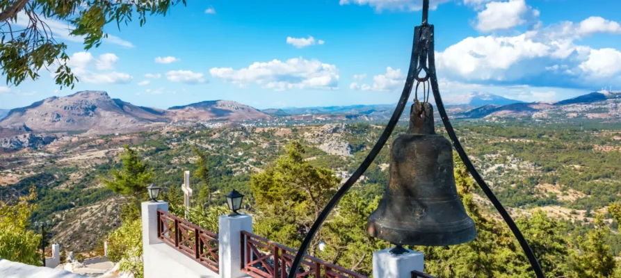 Old tall bell in the foreground and overlooking the magnifient view of the land and mounts from the Tsambika Monastery, Rhodes, Greece